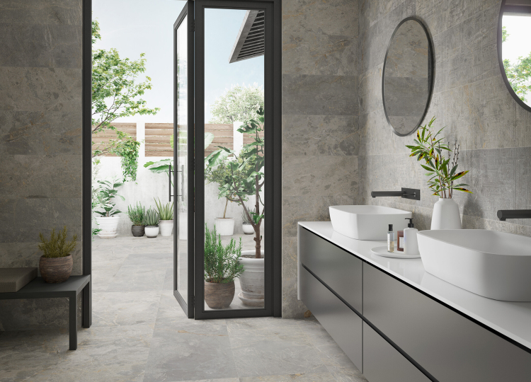 Modernen Badezimmer mit Türe auf die Terrasse, graue Bodenfliesen und Wandfliesen in Steinoptik, Waschtisch mit 2 Waschbecken